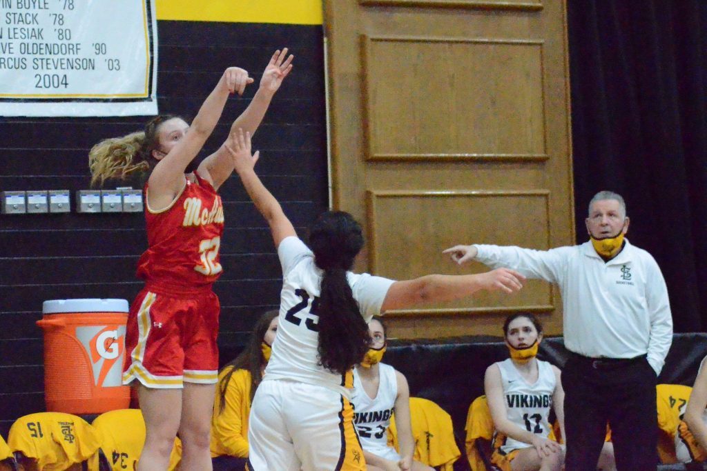 Mother McAuley’s Bella Finnegan launches a 3-point attempt over St. Laurence’s Lilliana Magana as Vikings coach George Shimko looks on in a game on Jan. 11. Finnegan scored her 1,000th career point in the game. Photo by Jeff Vorva