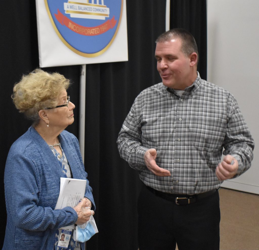 Michael Medeisis chats with village Trustee Norma Pinion after the board promoted him
to the rank of fire battalion chief. (Photo by Steve Metsch)