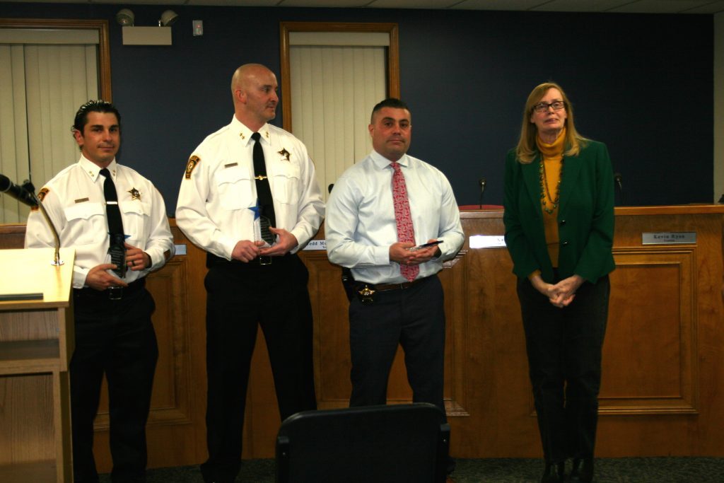 Worth Mayor Mary Werner congratulates three police officers who recently earned master degrees. Deputy chiefs (from left) Robert Peterson and Christiano Fernandez, and Tim Denton, the police chief, were honored during the Worth Village Board meeting on Tuesday night. (Photo by Joe Boyle)