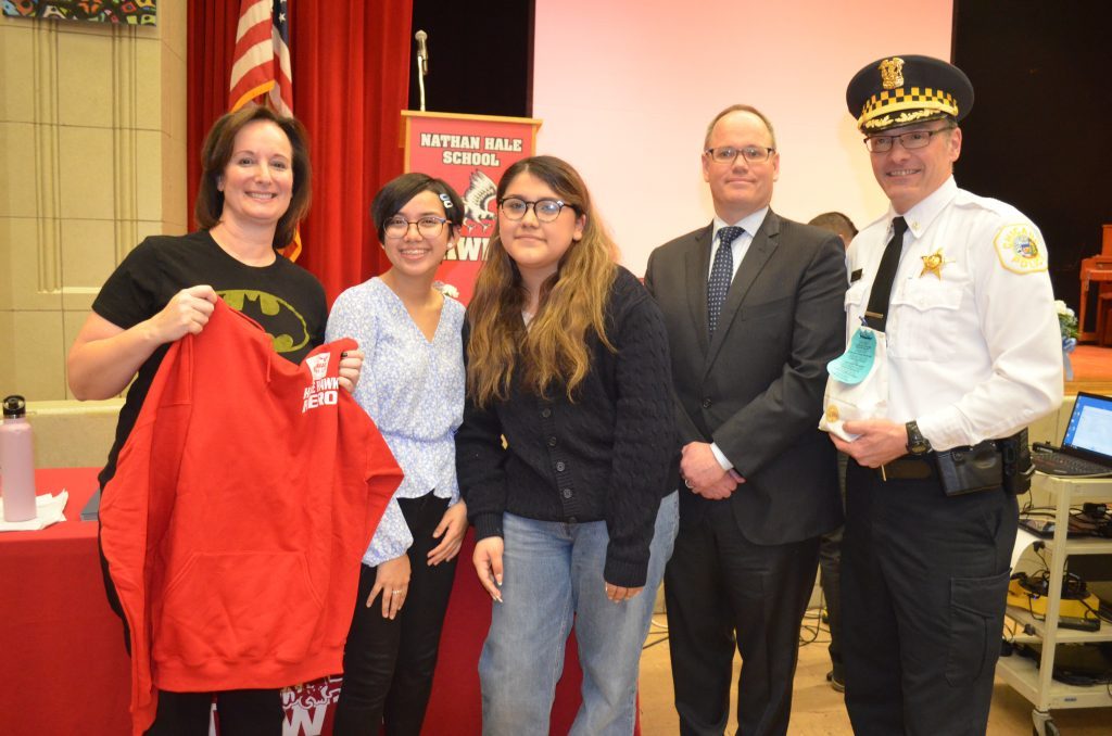 Showing one of the red Hawk Heroes shirts given to police, are (from left) Hale Principal Dawn Iles-Gomez, eighth graders Maria Ramirez and Delia Gonzalez, 13th Ward Ald. Marty Quinn and Chicago Lawn (8th) District Commander Bryan Spreyne. --Photo by Cosmo Hadac
