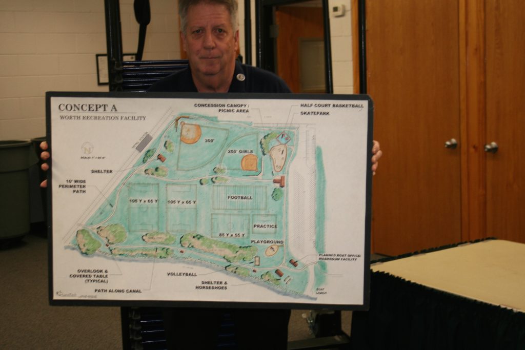 Bob O'Shaughnessy, supervisor for the Worth Park District, holds up a sign that shows a plan for development of Altman Park that dates back to the early 1980s. A resolution was passed by the Worth Village Board that will allow Altman Park to be managed by the park district through a lease agreement with the Metropolitan Water Reclamation District of Greater Chicago. (Photos by Joe Boyle)