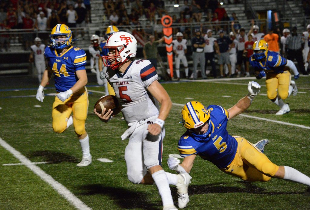 St. Rita quarterback Jett Hilding gains a chunk of his 66 rushing yards in the Mustangs' 42-21 win over Sandburg on Aug. 25. Photo by Jason Maholy