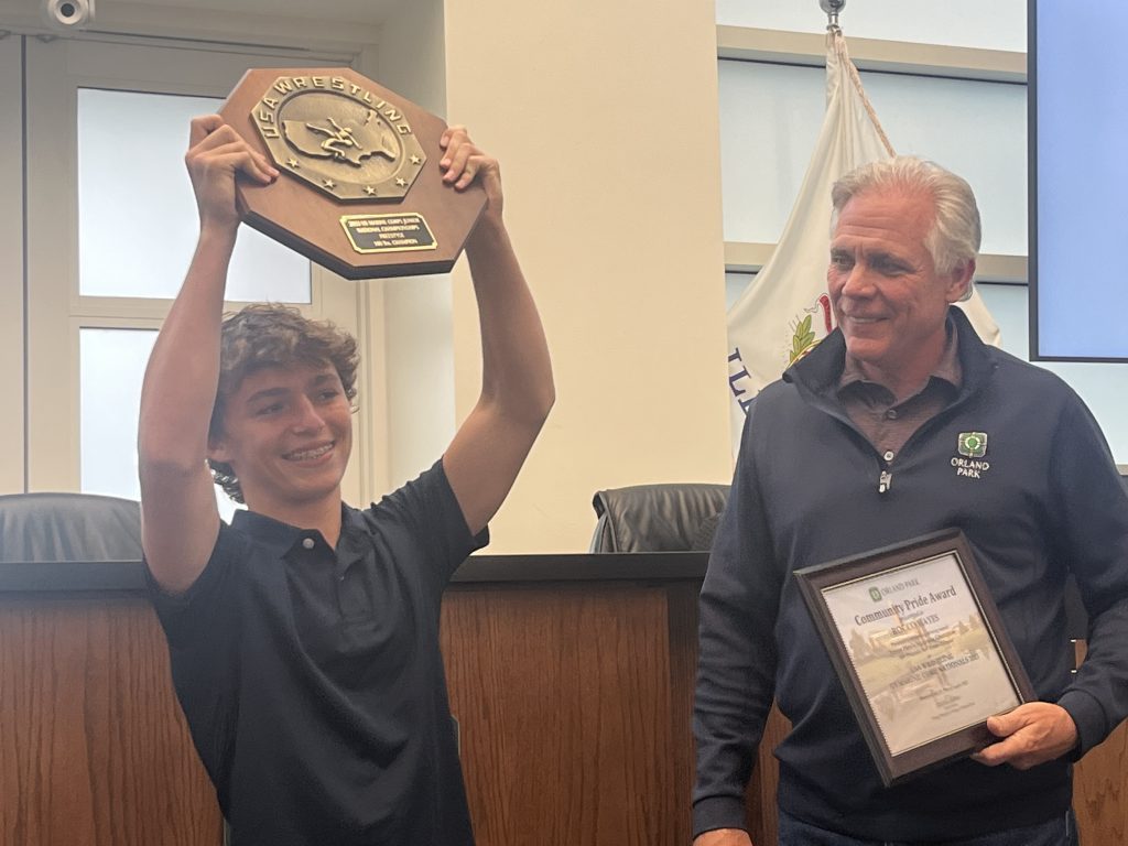 Sandburg junior Rocco Hayes shows his national championship award to Orland Park Mayor Keith Pekau and the audience on Aug. 7. The Orland Park Board of Trustees honored Hayes. Photo by Jeff Vorva