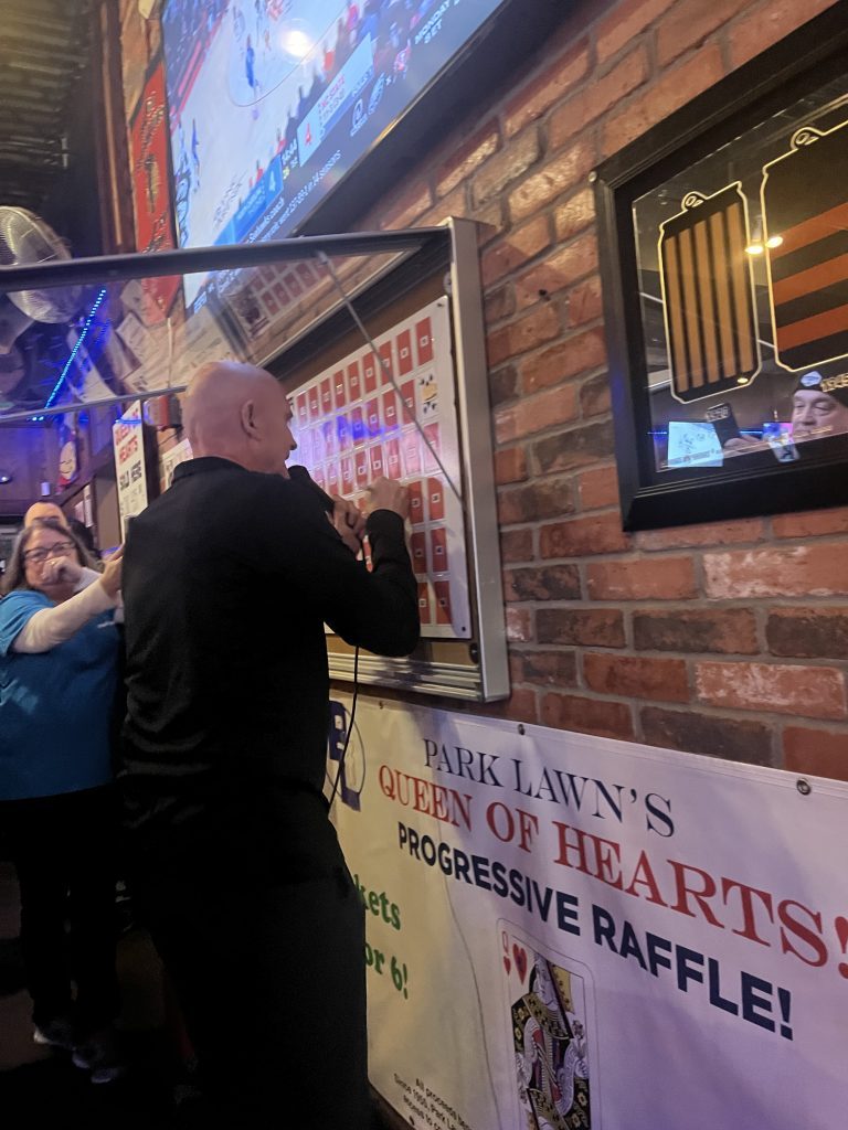 Tim Newsome, owner of At the Office Sports Bar, reveals the card chosen at the Queen of Hearts drawing held Jan. 10 at his bar at 4901 W. Cal-Sag Road in Crestwood. (Photo by Dermot Connolly)