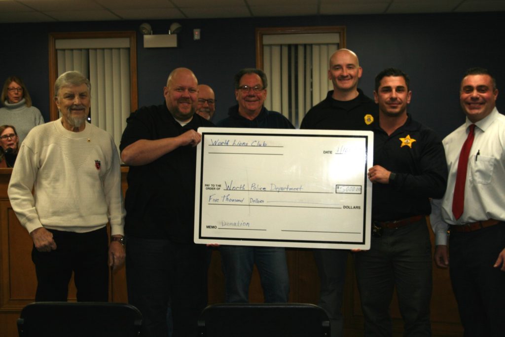 Worth Police Chief Tim Denton (far right) joins members of the department and the Worth Lions Club after the organization donated $5,000 to the police department. (Photo by Joe Boyle)