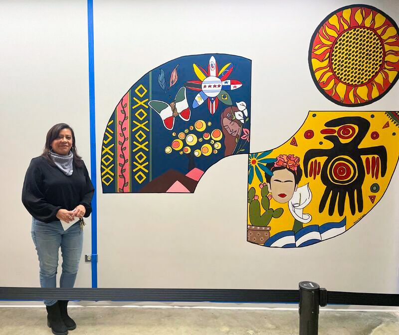 Artist Bianca Rodriguez, director of Richard J. Daley College’s Transfer Center, poses with her mural. --Supplied photo