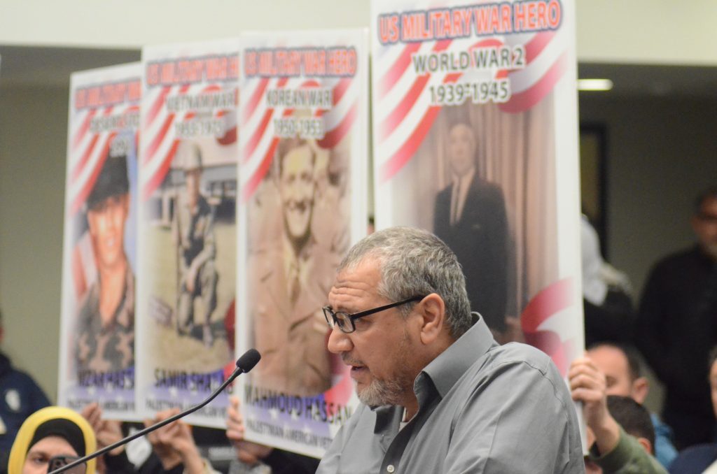 Orland Park's Fawzy Hassan speaks to the Orland Park Village Board on Monday in front of a backdrop of posters of members of his family who served the United States in wartime. (Photo by Jeff Vorva)