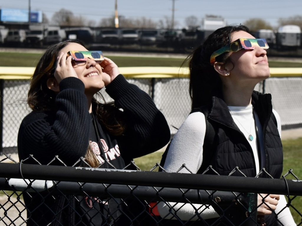 Teacher aides Julyssa Gaytan (left) and Rebeka Tovar were thrilled to witness the eclipse at Argo High’s football stadium. (Photo by Steve Metsch)
