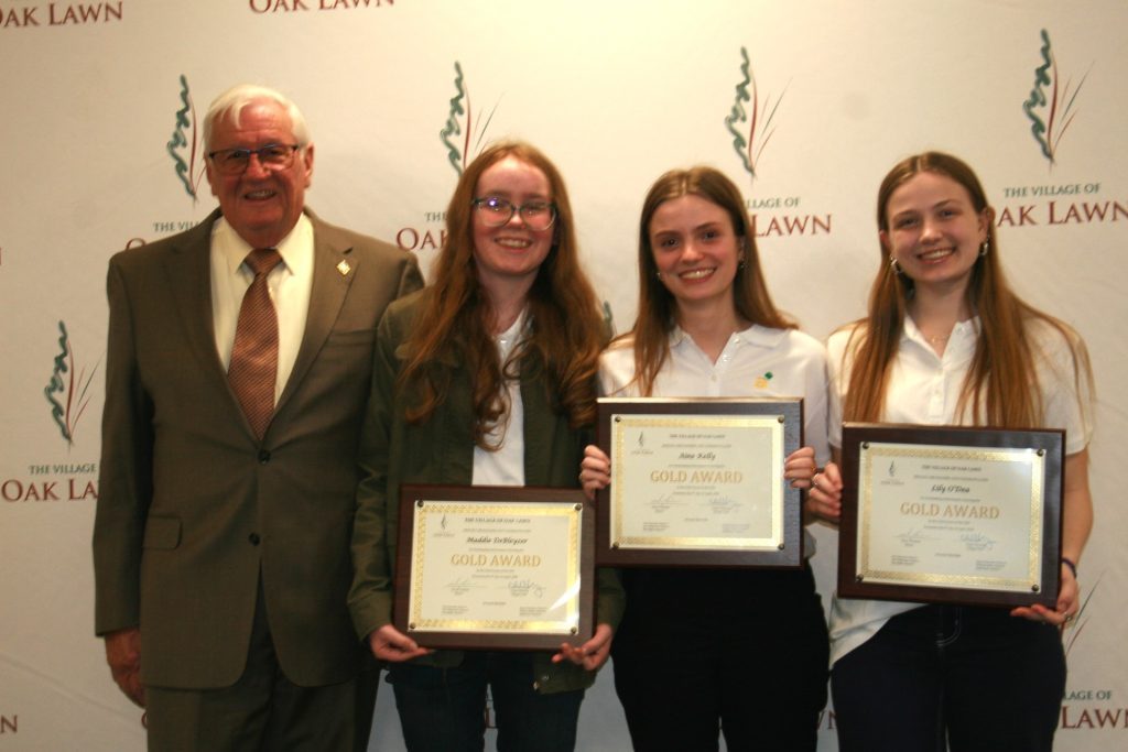 Oak Lawn Mayor Terry Vorderer joins Girl Scout Gold Award winners (from left) Maddie DeBleyzer, Aine Kelly and Lilly O'Dea during the village board meeting on Tuesday night. (Photo by Joe Boyle)