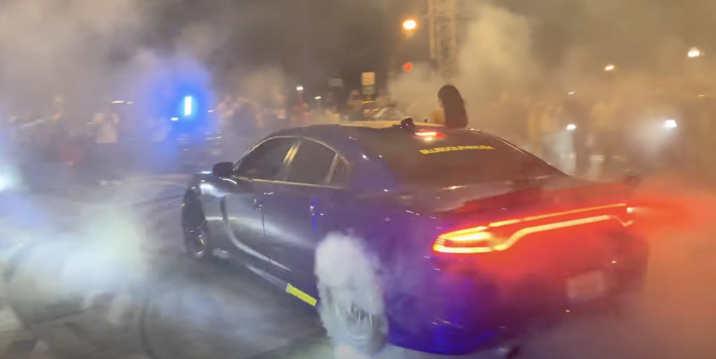 In a screenshot from a video showing drifting in a Southwest Side parking lot, Smoke billows from both a muscle car's wheels and the asphalt below. --Supplied photo