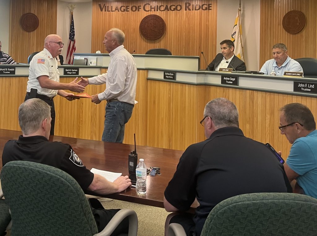 Retiring Chicago Ridge Fire Chief William Bonnar (at left) is congratulated by Mayor Jack Lind, who also presented him with a proclamation, at the June 18 Village Board meeting. (Photo by Dermot Connolly)